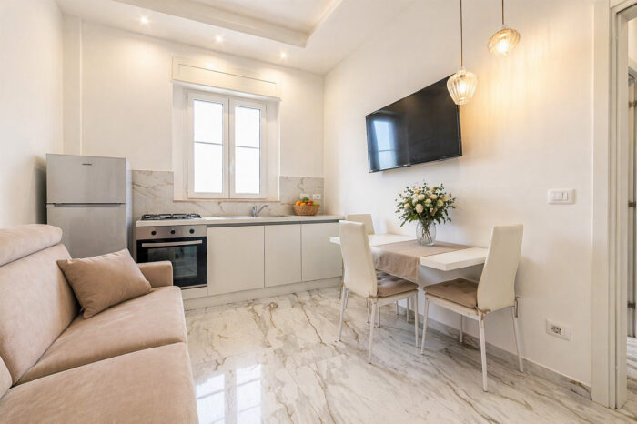 Zona living con cucina del Fronte Mare Apartment a Gallipoli con tavolo da pranzo e divano by Symphonya Luxury Holiday Rentals
